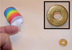 Paint washer gold, tie thread to it and attach the other end of the thread to the tube.